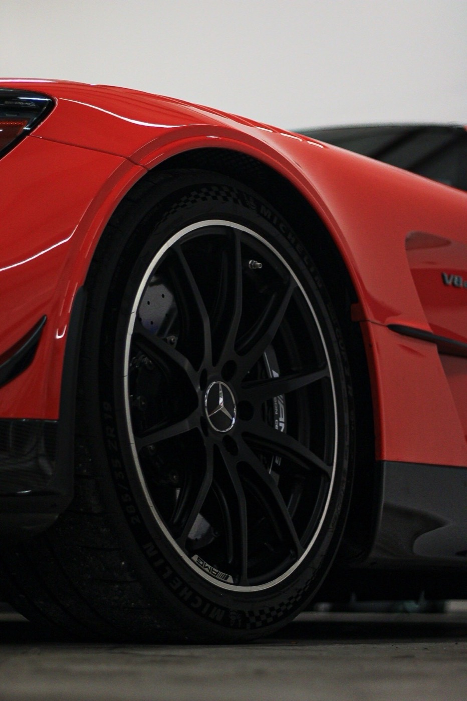 Black alloy wheel and red fender of a freshly detailed AMG on the shop floor